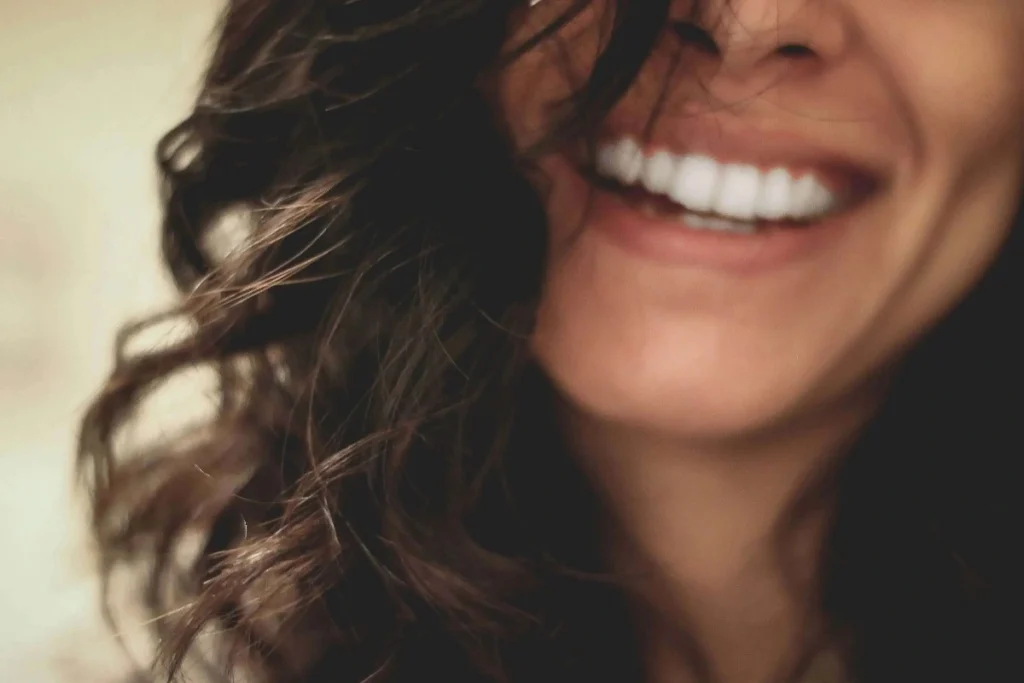 Smiling woman with long brown hair showing her teeth, symbolizing dental health and dreams about teeth