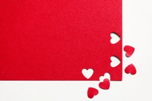 Red paper with cut-out hearts symbolizing love, romance, and sacred marriage