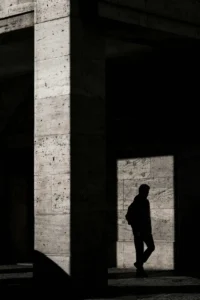 shadow of a man walking away, reflected on a square in a brick wall